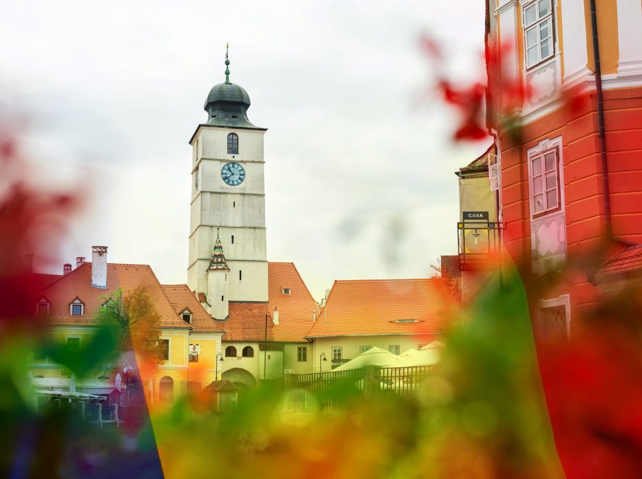 View of the Historic Centre of Sibiu. Street with Council Tower, old buildings made in national style and flowers on the foreground