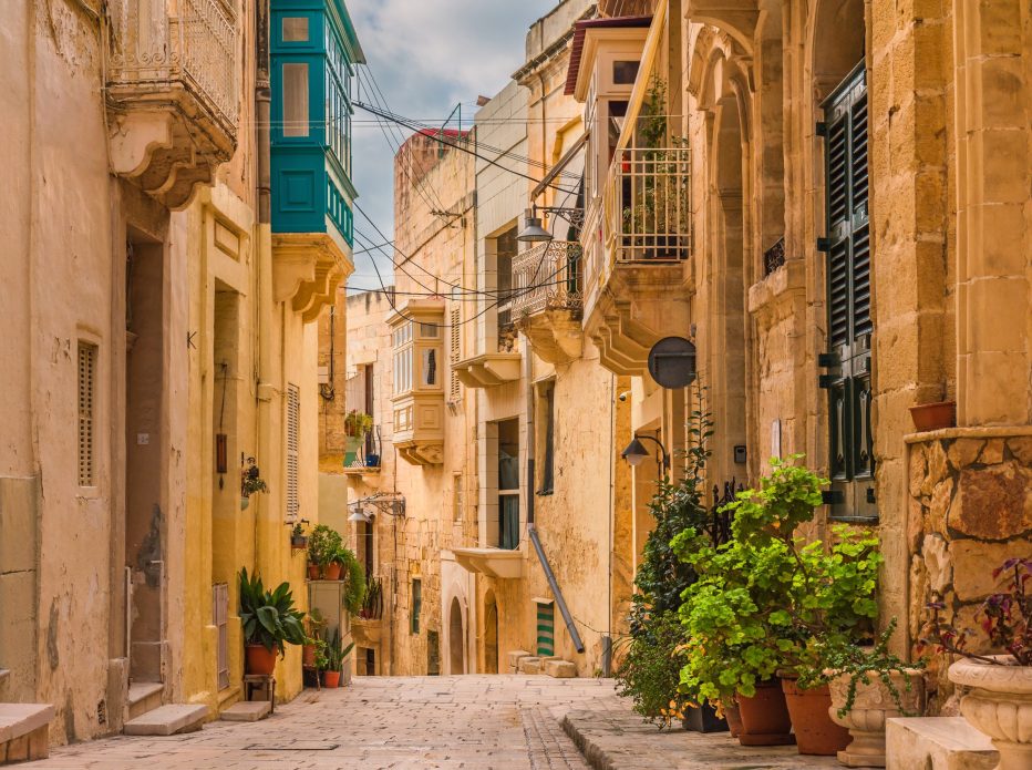 Old medieval street with yellow buildings, beautiful balconies and flower pots in Birgu, Valletta, Malta with nobody